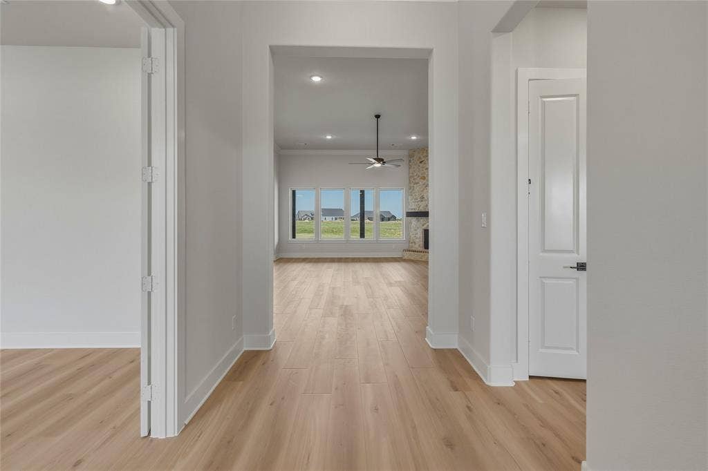 2305 Gypsum Street, Krum, TX 76249 Light wood-finish flooring extending into an open living area featuring a stone fireplace, large windows, and a ceiling fan