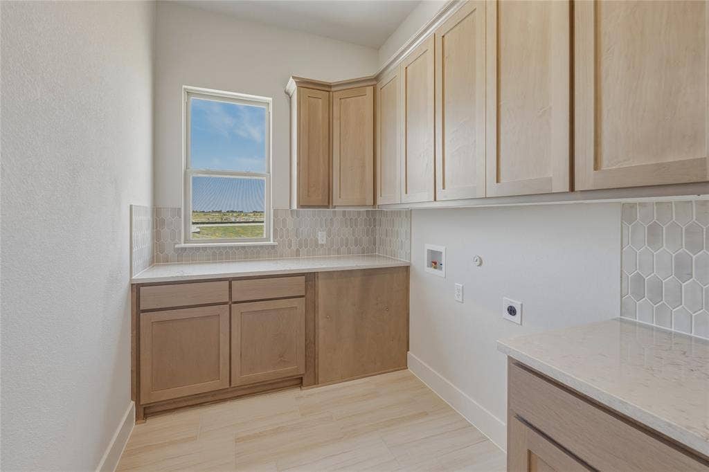 2305 Gypsum Street, Krum, TX 76249 Light wood-finish cabinetry, light-toned countertops, and geometric tile backsplash