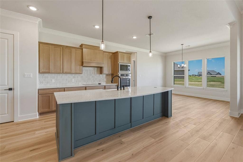 2305 Gypsum Street, Krum, TX 76249 Spacious kitchen featuring a large central island with a light-toned countertop, wood-finish flooring, and light natural wood cabinetry