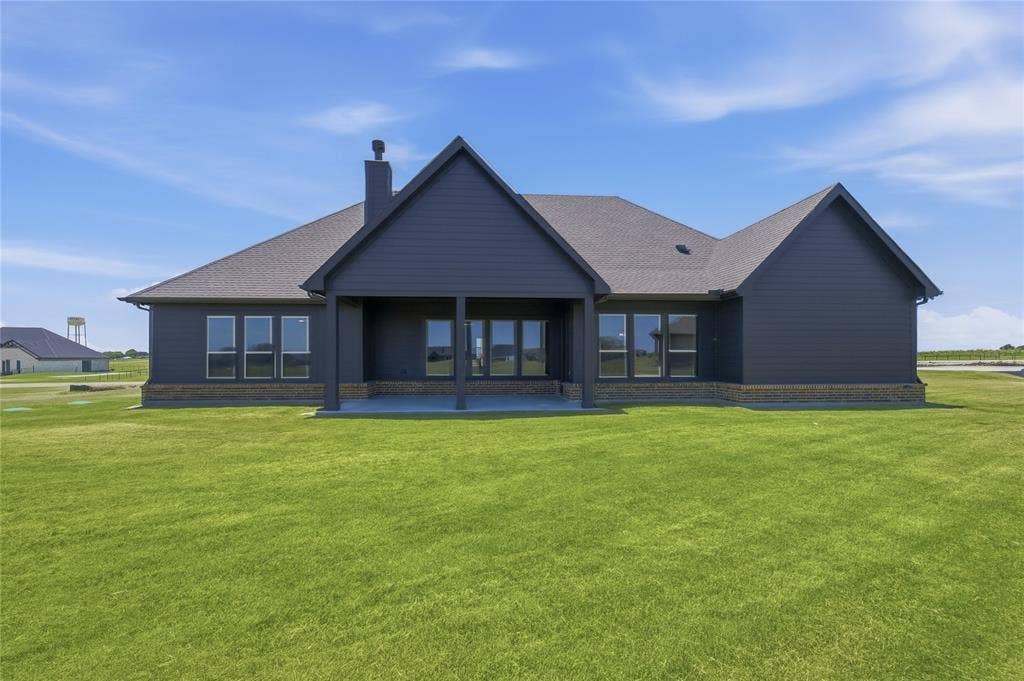 2305 Gypsum Street, Krum, TX 76249 Expansive backyard featuring a covered patio, dark siding, and a stone-clad foundation