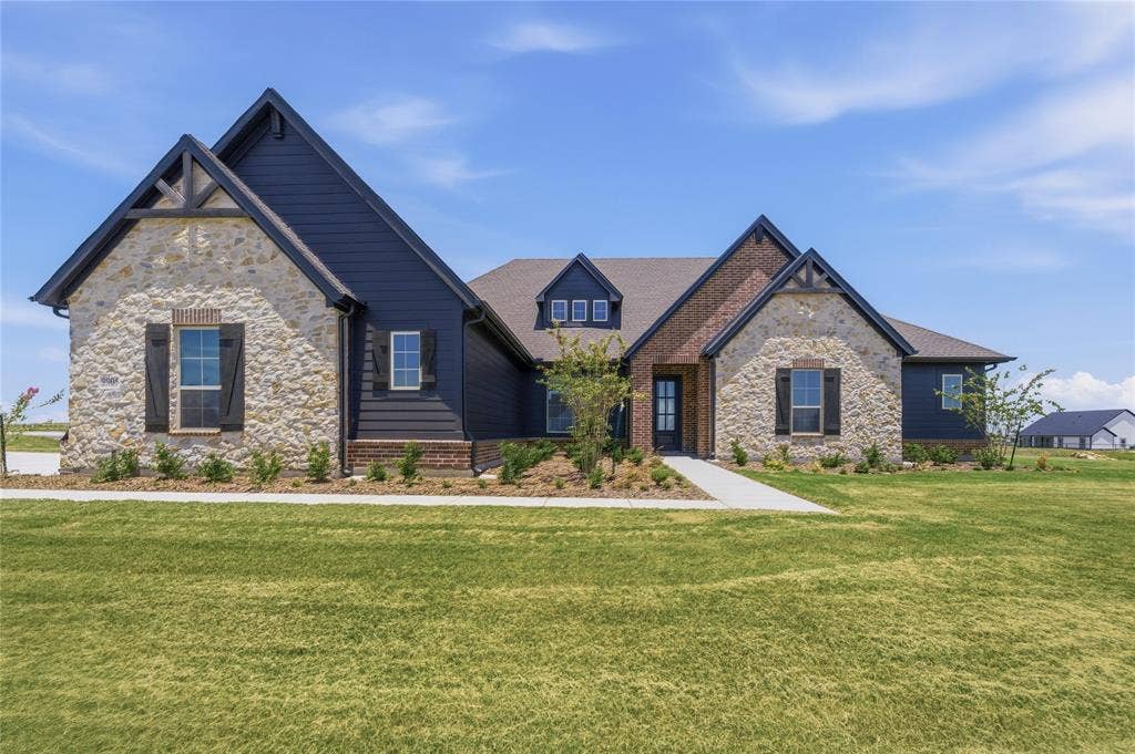 2305 Gypsum Street, Krum, TX 76249 Stone and siding exterior featuring dark trim, a covered entry, and dormer windows