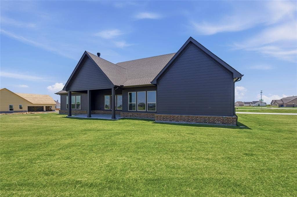 2305 Gypsum Street, Krum, TX 76249 Contemporary exterior featuring dark horizontal siding and a brick skirting