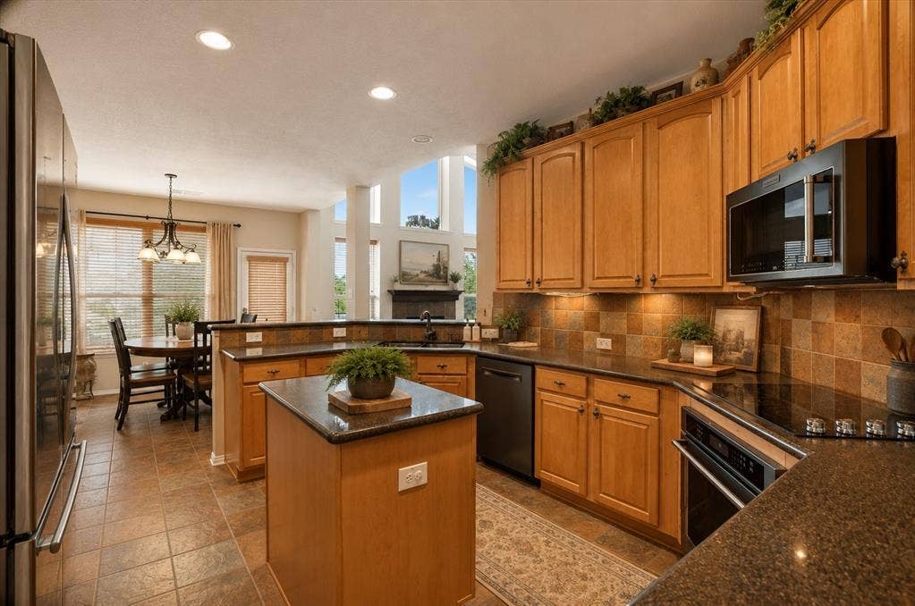 5212 Whisper Drive, Fort Worth, TX 76123 Virtually staged Kitchen featuring wood cabinetry, dark countertops, tiled flooring, an integrated microwave, and an electric range
