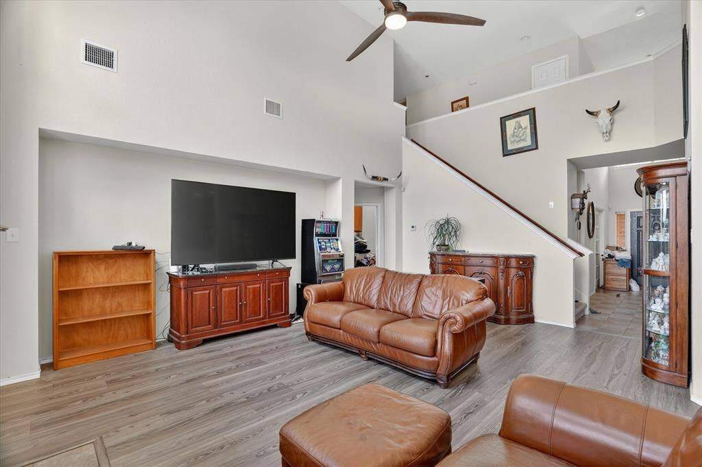5212 Whisper Drive, Fort Worth, TX 76123 Spacious living area featuring vaulted ceilings, wood-finish flooring, a ceiling fan, and staircase access to an upper level