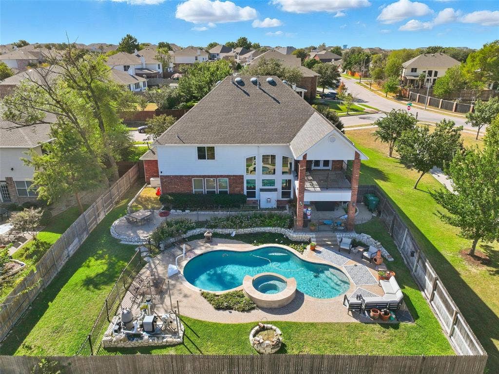5212 Whisper Drive, Fort Worth, TX 76123 Back of property featuring a patio area, a fenced backyard, a pool with connected hot tub, brick siding, and a residential view