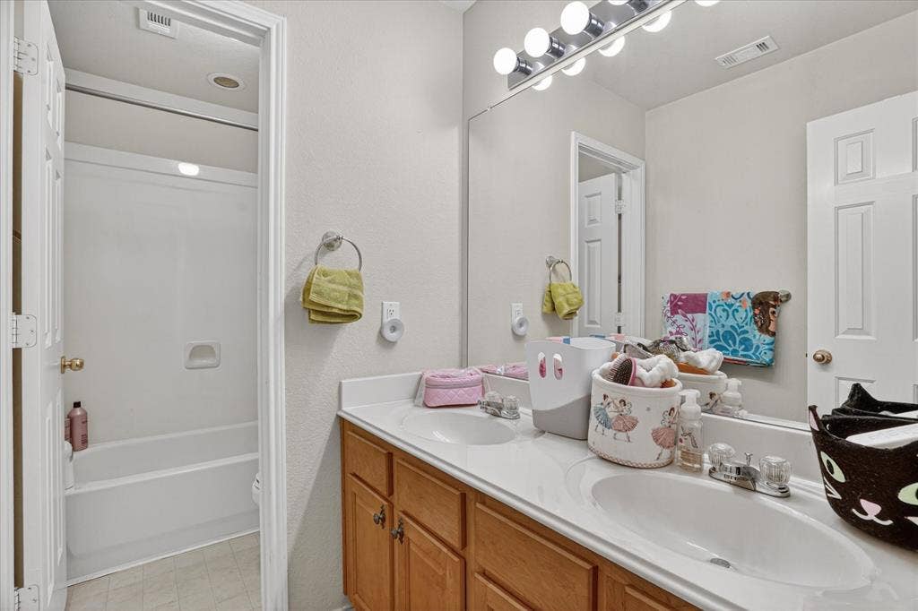 5212 Whisper Drive, Fort Worth, TX 76123 Double vanity with integrated sinks, laminate countertops, and wood-finish cabinetry