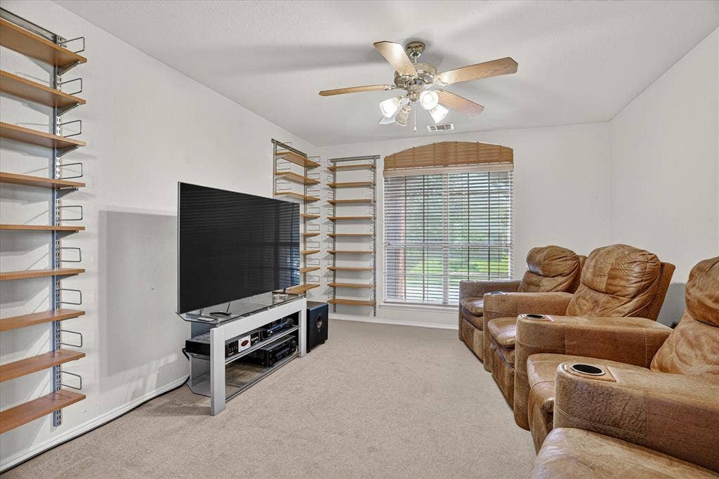 5212 Whisper Drive, Fort Worth, TX 76123 Carpeted interior room featuring a window with horizontal blinds, a ceiling fan with light fixture, and built-in adjustable shelving systems on opposing walls