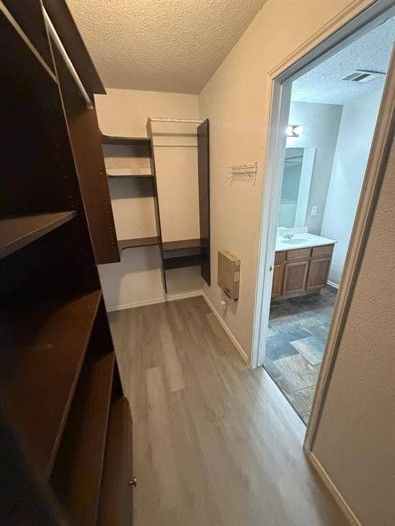 Walk-in closet featuring extensive built-in shelving, hanging rods, and light wood-finish flooring