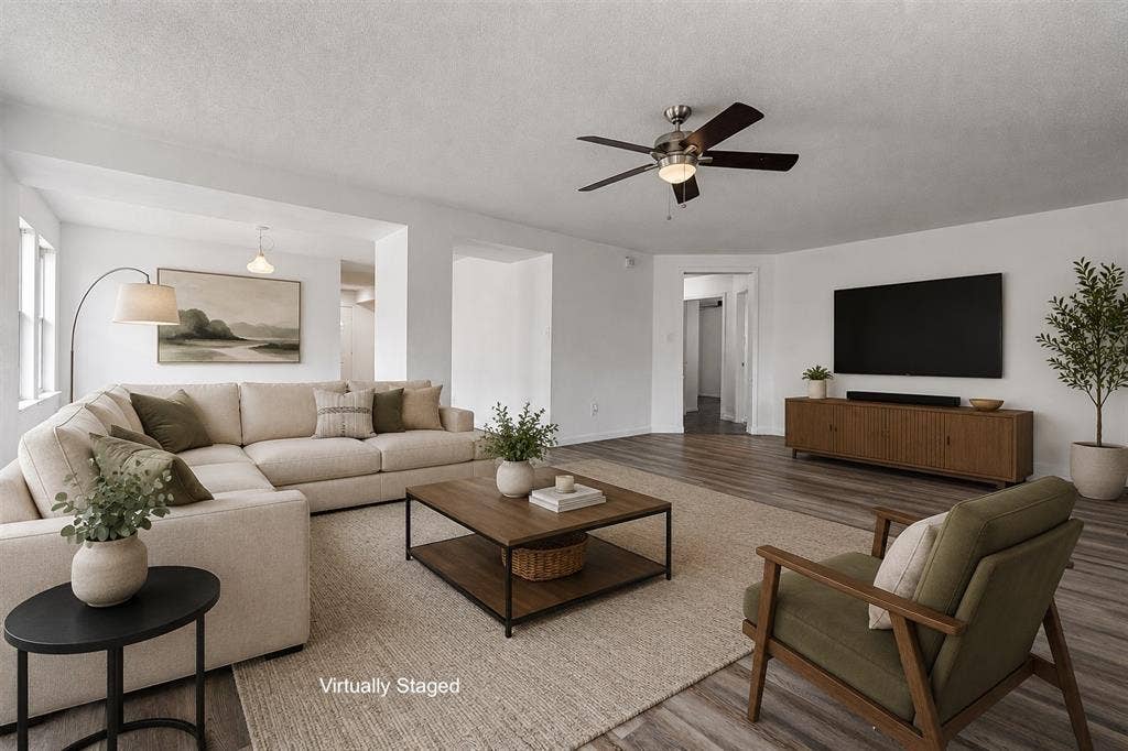 Open-concept living space featuring wood-finish flooring, white walls, and a ceiling fan with integrated lighting