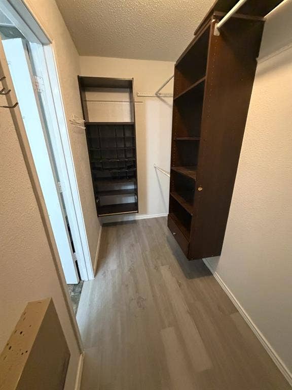 Walk-in closet featuring light wood-finish flooring