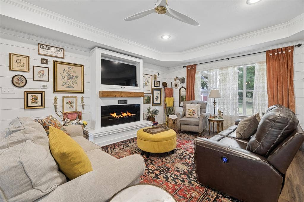 25 Starview Drive, Star Harbor, TX 75148 Living area featuring a ceiling fan, ornamental molding, a fireplace, wood floors, and wood walls