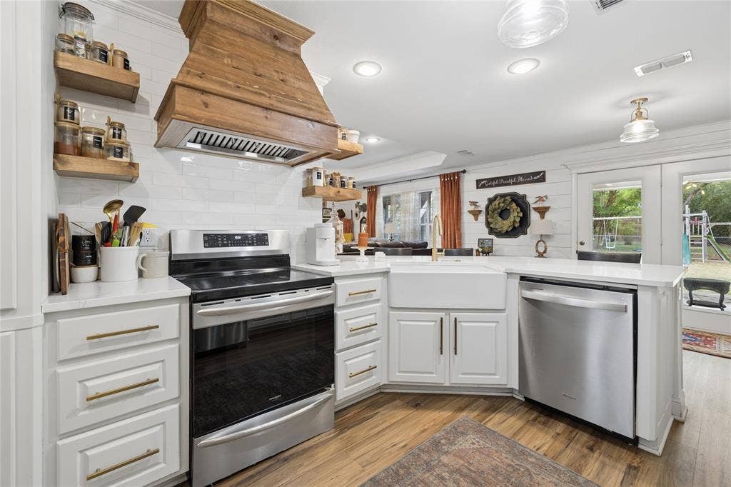 25 Starview Drive, Star Harbor, TX 75148 Kitchen featuring a peninsula, stainless steel appliances, light wood finished floors, white cabinetry, and open shelves