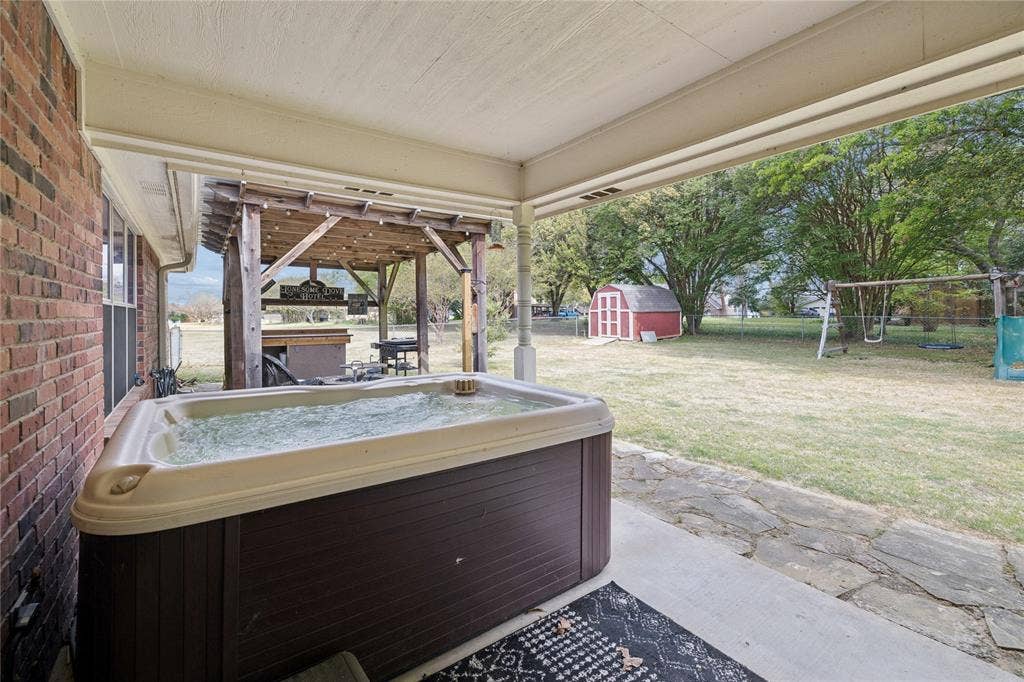 25 Starview Drive, Star Harbor, TX 75148 View of patio featuring a hot tub and a storage shed