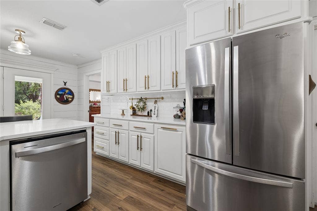 25 Starview Drive, Star Harbor, TX 75148 Kitchen with stainless steel appliances, wood ffloors, white cabinetry, ornamental molding, and light stone counters