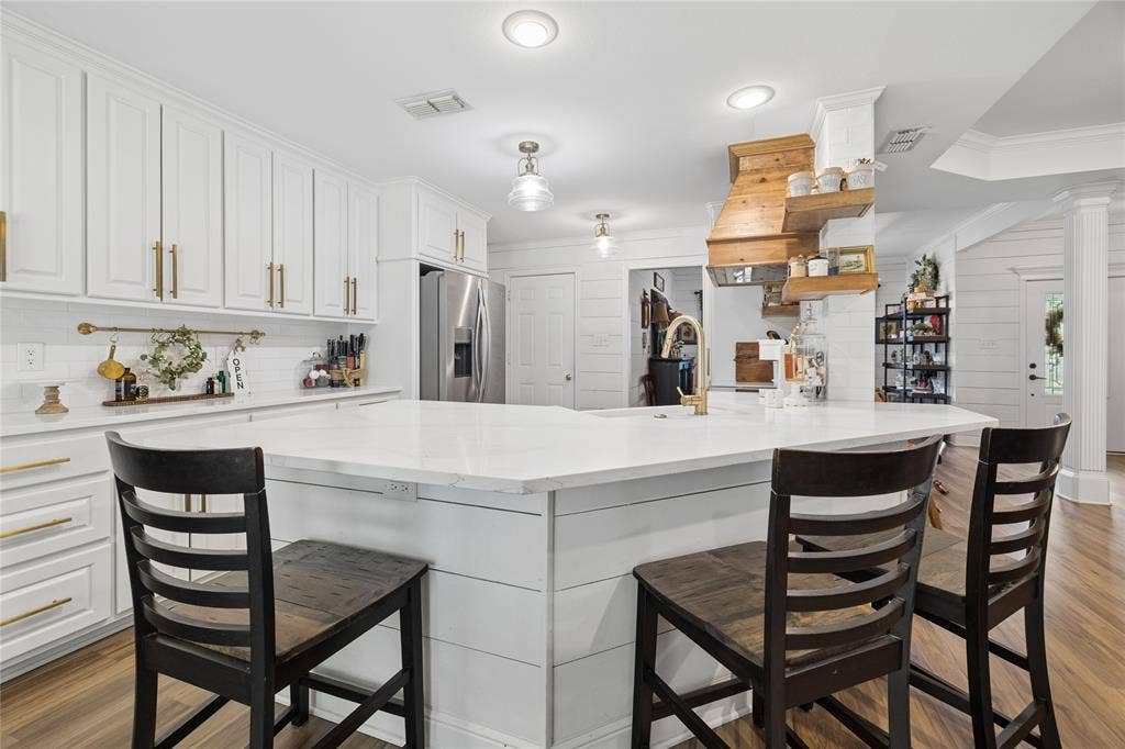 25 Starview Drive, Star Harbor, TX 75148 Kitchen featuring light wood flooring, white cabinets, light stone counters, crown molding, and a peninsula