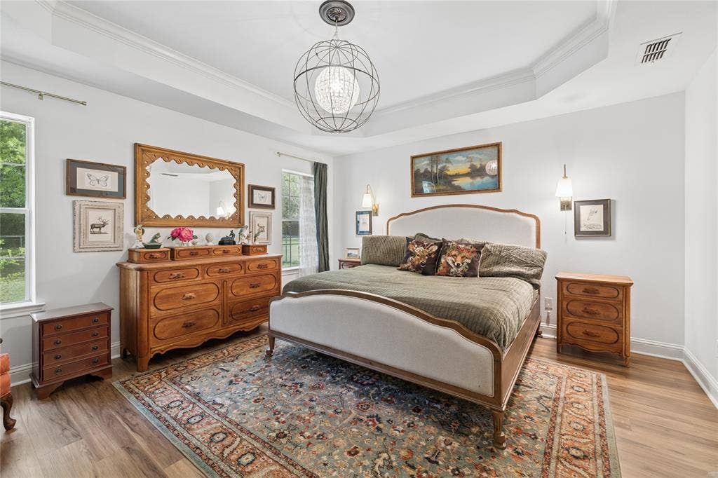 25 Starview Drive, Star Harbor, TX 75148 Bedroom with ornamental molding, light wood-type flooring, a chandelier, and a raised ceiling
