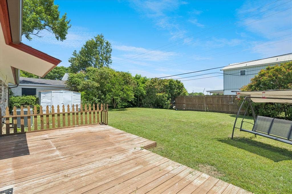 5820 Shipp Drive, Watauga, TX 76148 Expansive backyard featuring a wood deck, manicured lawn, and mature trees