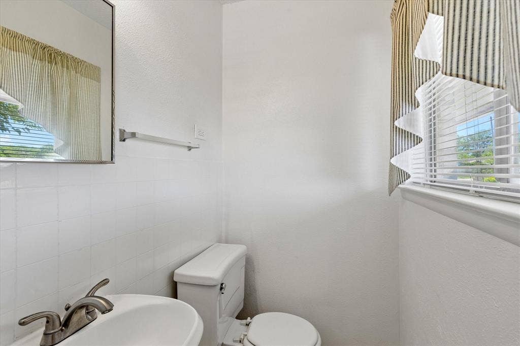 5820 Shipp Drive, Watauga, TX 76148 Compact bathroom with a pedestal sink, brushed nickel faucet, and a wall-mounted mirror