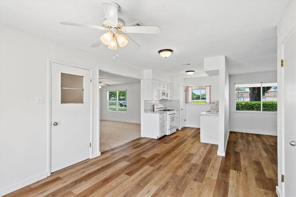 5820 Shipp Drive, Watauga, TX 76148 Open-concept living space featuring wood-finish flooring, white walls, and a ceiling fan with light fixture