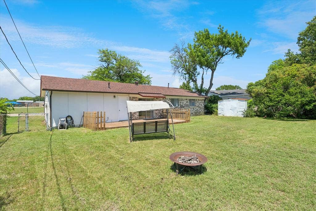 5820 Shipp Drive, Watauga, TX 76148 Expansive grass lawn featuring a wood deck, perimeter fencing, and mature trees