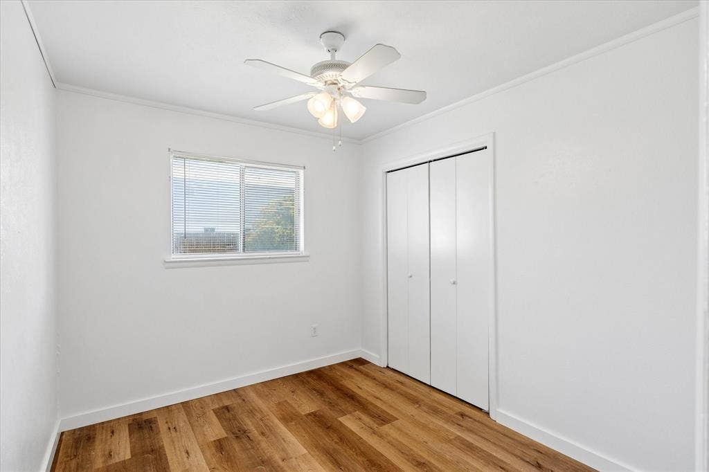 5820 Shipp Drive, Watauga, TX 76148 Light-filled interior space featuring wood-finish flooring, a ceiling fan with integrated lighting, a window with horizontal blinds, and bi-fold closet doors