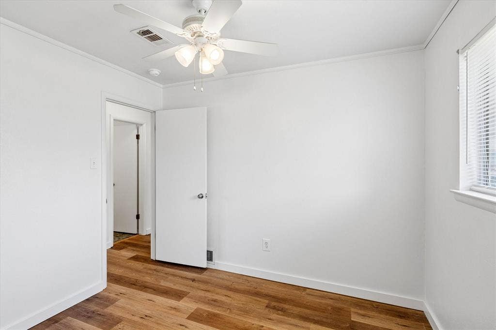 5820 Shipp Drive, Watauga, TX 76148 Interior room featuring wood-finish flooring, white walls, and a white ceiling fan with integrated lighting
