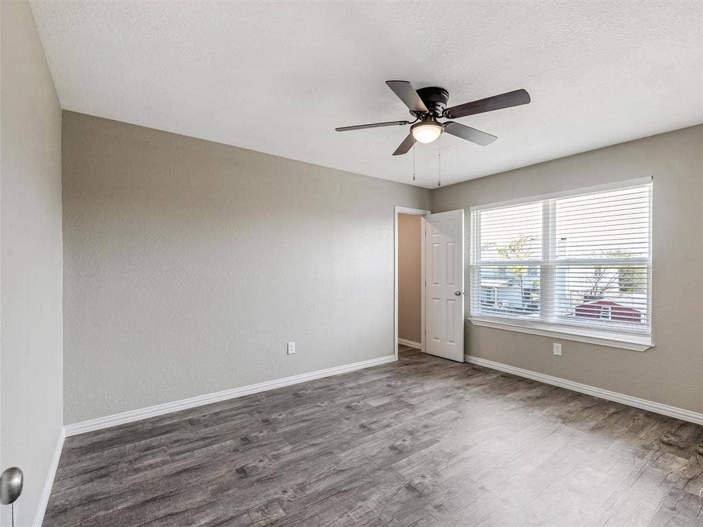 Bedroom featuring light gray wall paint, wood-finish flooring, and a ceiling fan with integrated lighting