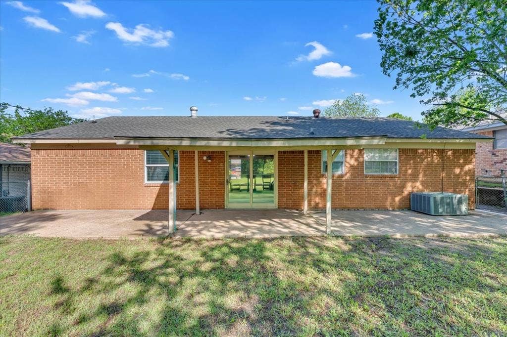 905 SE 3rd Street, Grand Prairie, TX 75051 Back of house with a patio area, brick siding, and roof with shingles