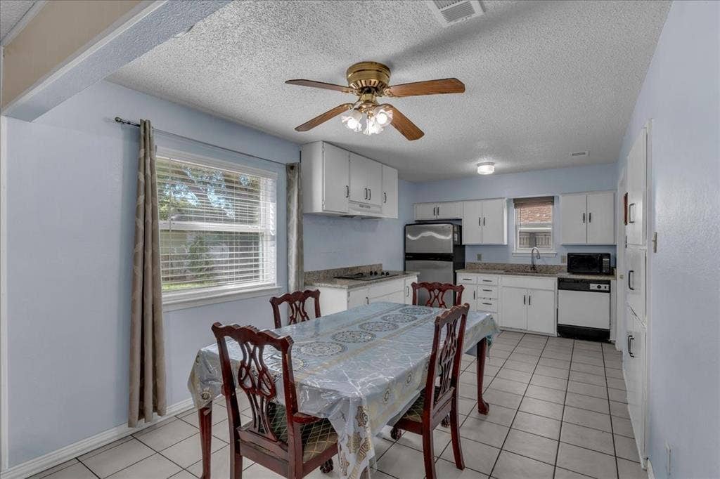 905 SE 3rd Street, Grand Prairie, TX 75051 Dining room with a ceiling fan, a textured ceiling, and light tile patterned floors