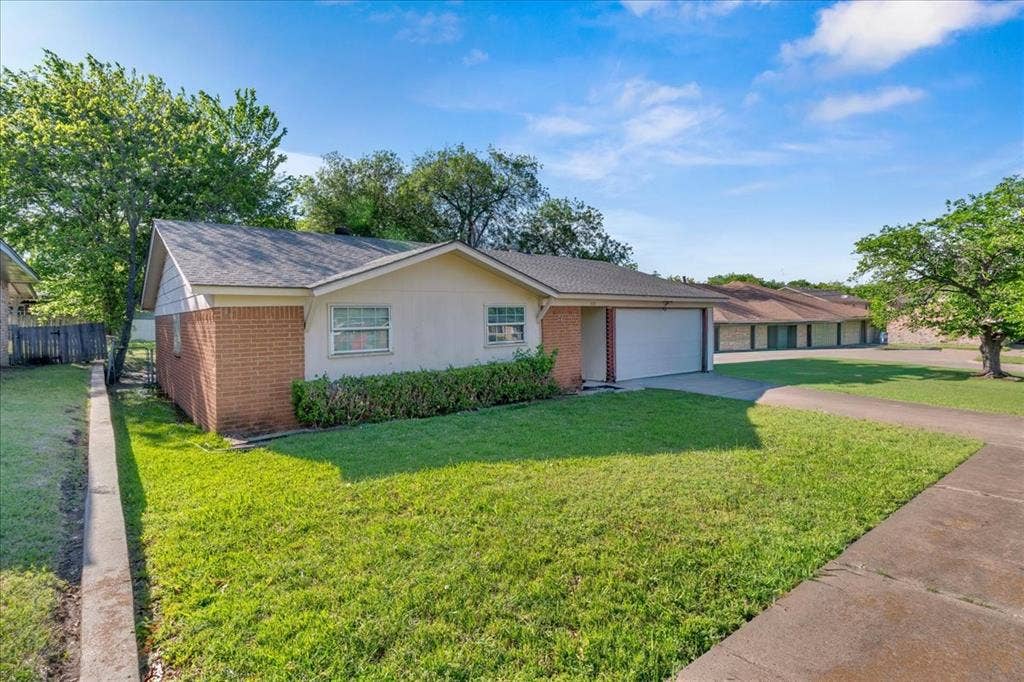 905 SE 3rd Street, Grand Prairie, TX 75051 View of front of home featuring brick siding, driveway, a garage, and roof with shingles
