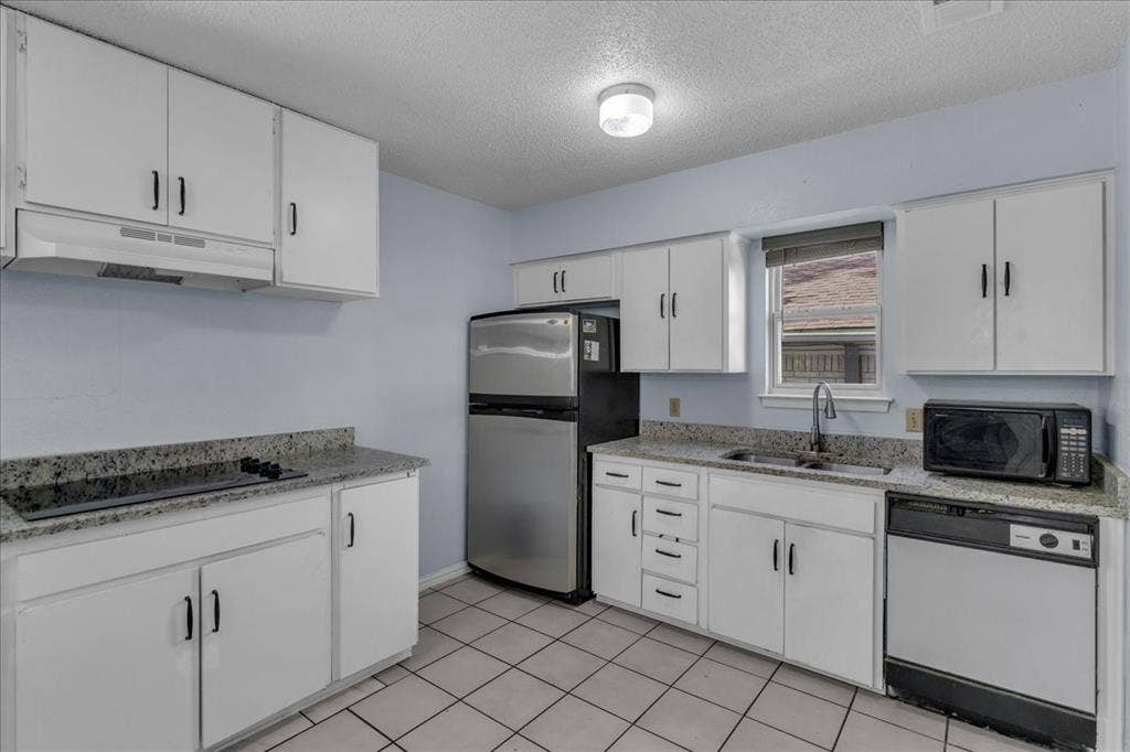 905 SE 3rd Street, Grand Prairie, TX 75051 Kitchen featuring white cabinetry, a textured ceiling, black appliances, light stone countertops, and light tile patterned floors