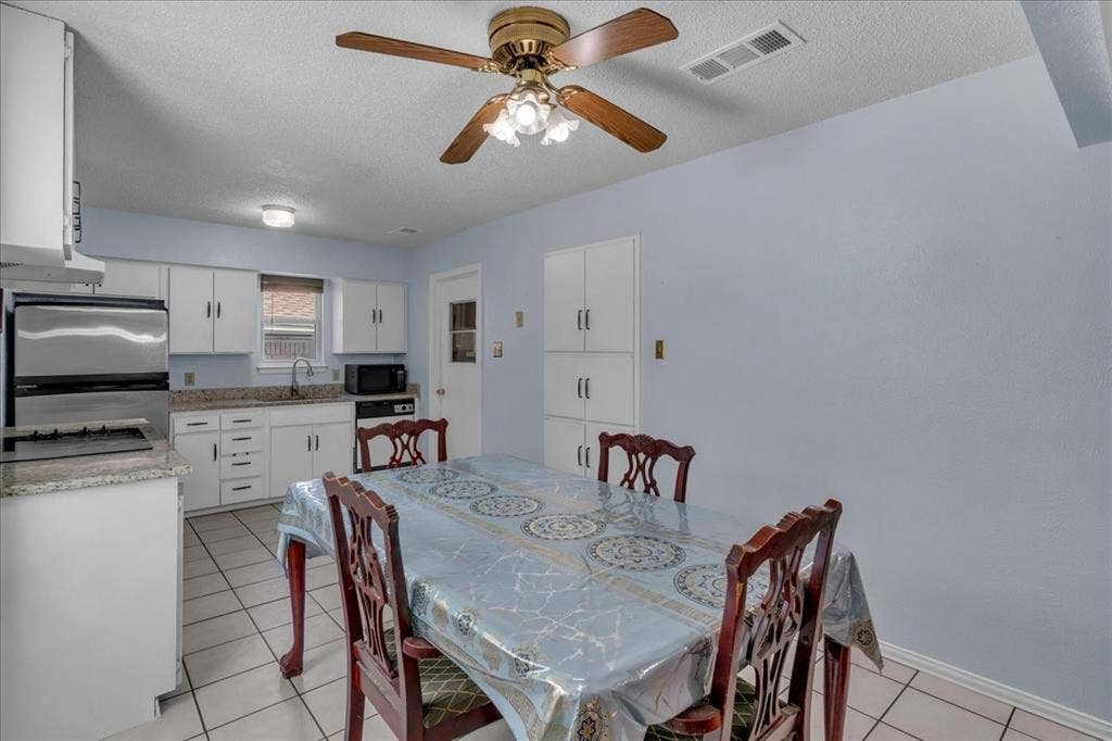 905 SE 3rd Street, Grand Prairie, TX 75051 Dining room with a textured ceiling, light tile patterned floors, and a ceiling fan