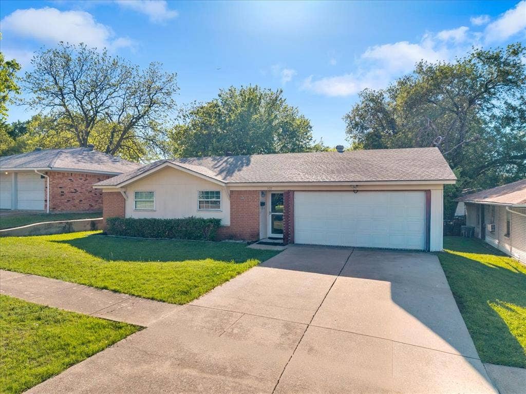 905 SE 3rd Street, Grand Prairie, TX 75051 Single story home with brick siding, a garage, a front yard, driveway, and roof with shingles