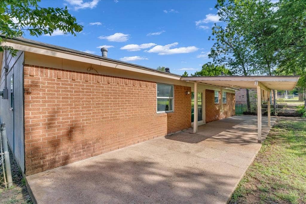 905 SE 3rd Street, Grand Prairie, TX 75051 View of side of home featuring an attached carport, a patio, and brick siding