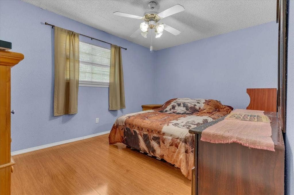 905 SE 3rd Street, Grand Prairie, TX 75051 Bedroom with light wood-style floors, ceiling fan, and a textured ceiling