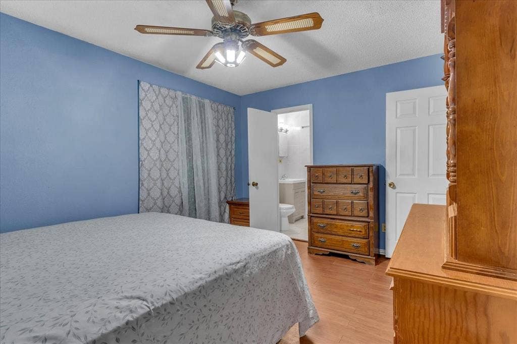 905 SE 3rd Street, Grand Prairie, TX 75051 Bedroom with light wood-style flooring, a ceiling fan, ensuite bathroom, and a textured ceiling