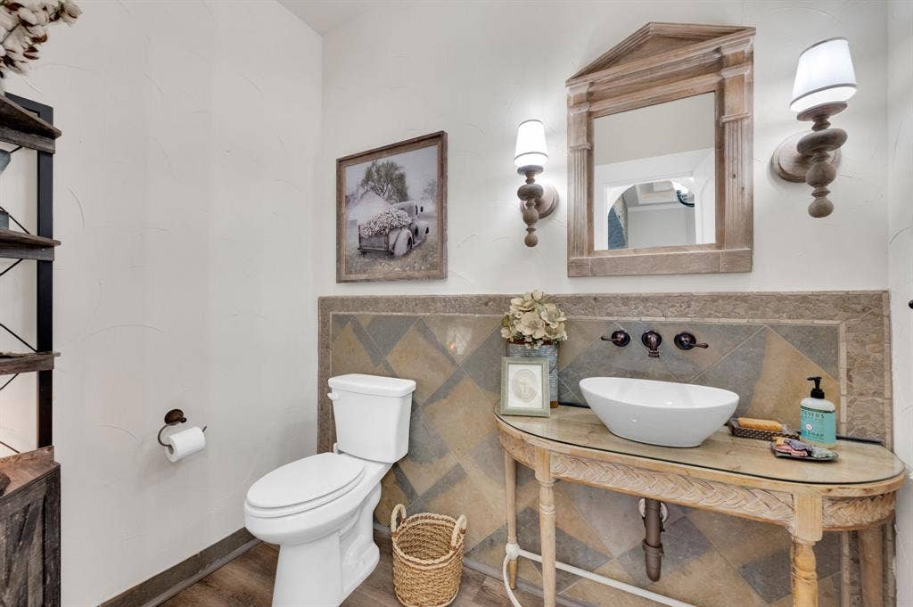 Half bath off the foyer with vessel sink, decorative tile accents, and designer lighting.