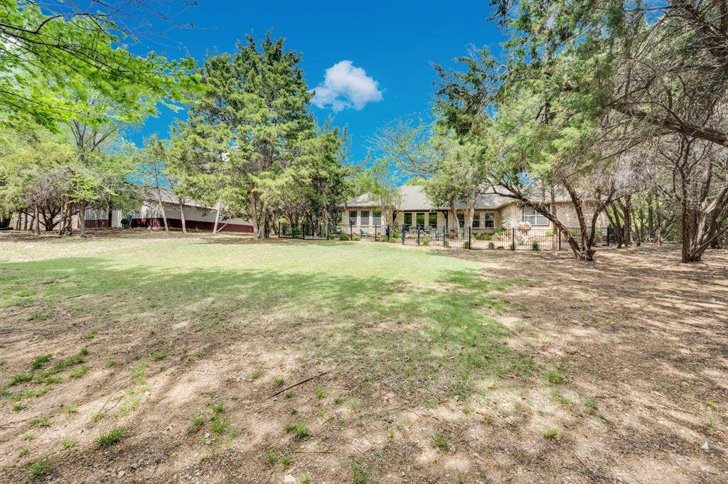 Spacious backyard with open green space, mature trees, and views of home and workshop.