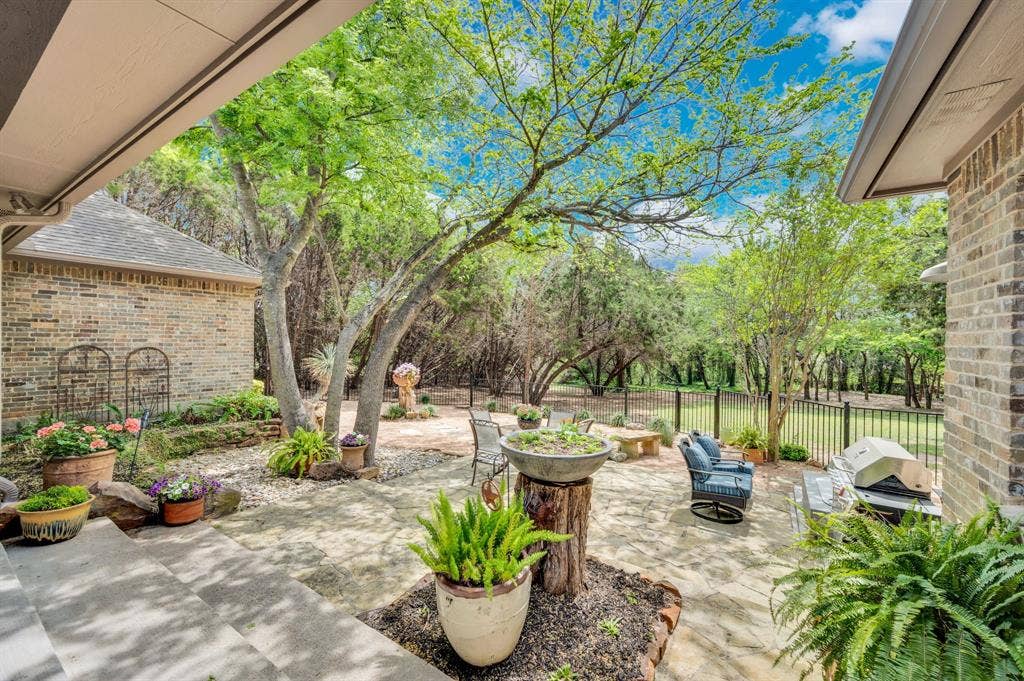Expanded view of patio showcasing grilling area, mature trees, and private backyard setting.
