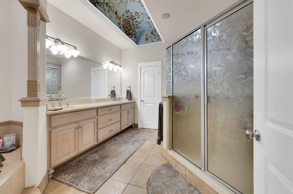 Walk-in shower and extended dual vanity in primary bath with ample storage.