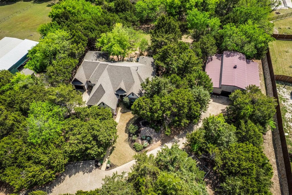 Aerial view of home and workshop surrounded by mature trees with private setting.