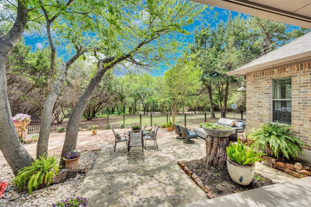 Covered patio with flagstone surface, outdoor seating, and peaceful treed views.