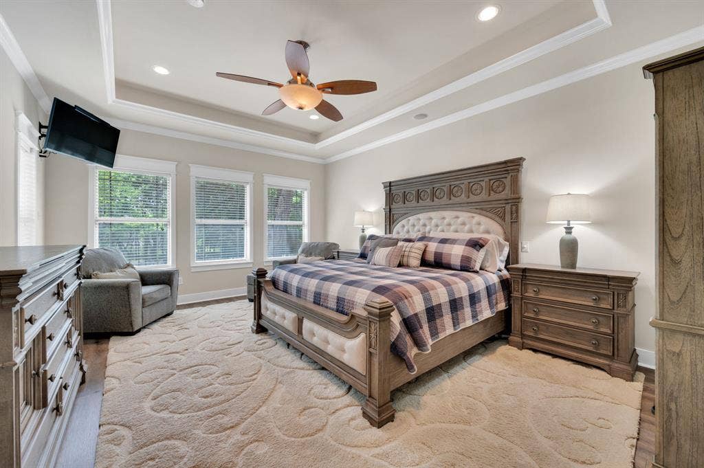 Spacious primary bedroom with tray ceiling, crown molding, and large windows for natural light.