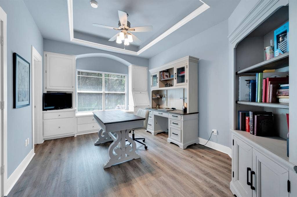 Guest bedroom with built-ins, large window, and wood flooring.