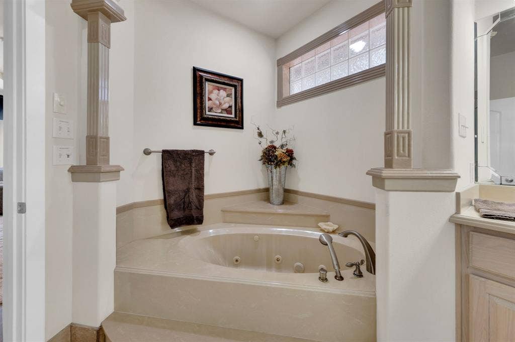 Jetted tub retreat with elevated surround and decorative accents.