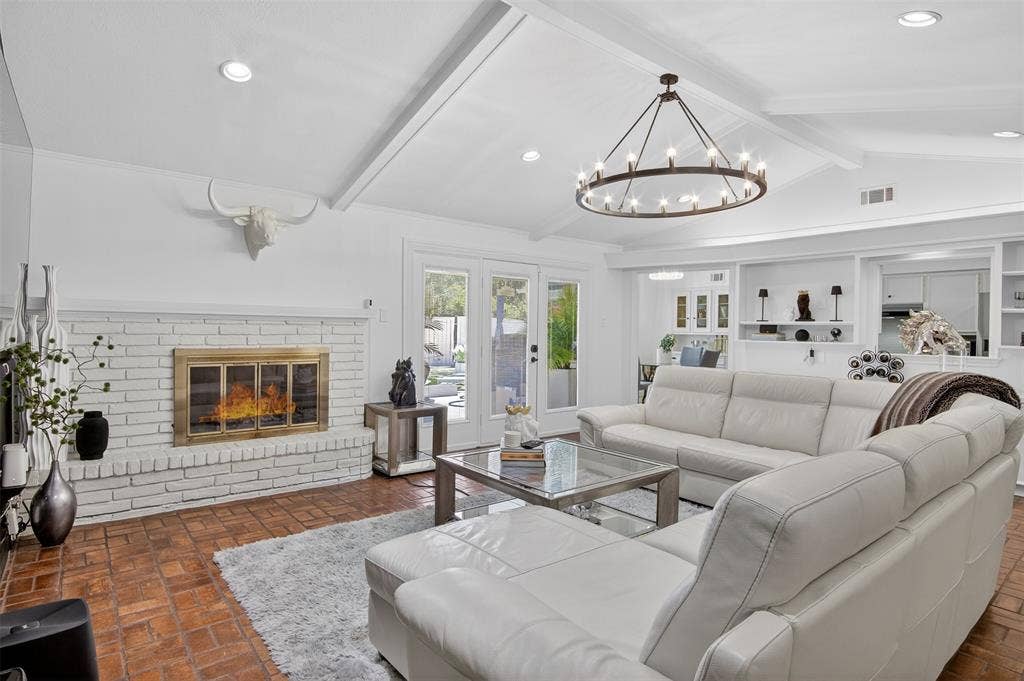 Living area with recessed lighting, a fireplace, beamed ceiling, and brick flooring