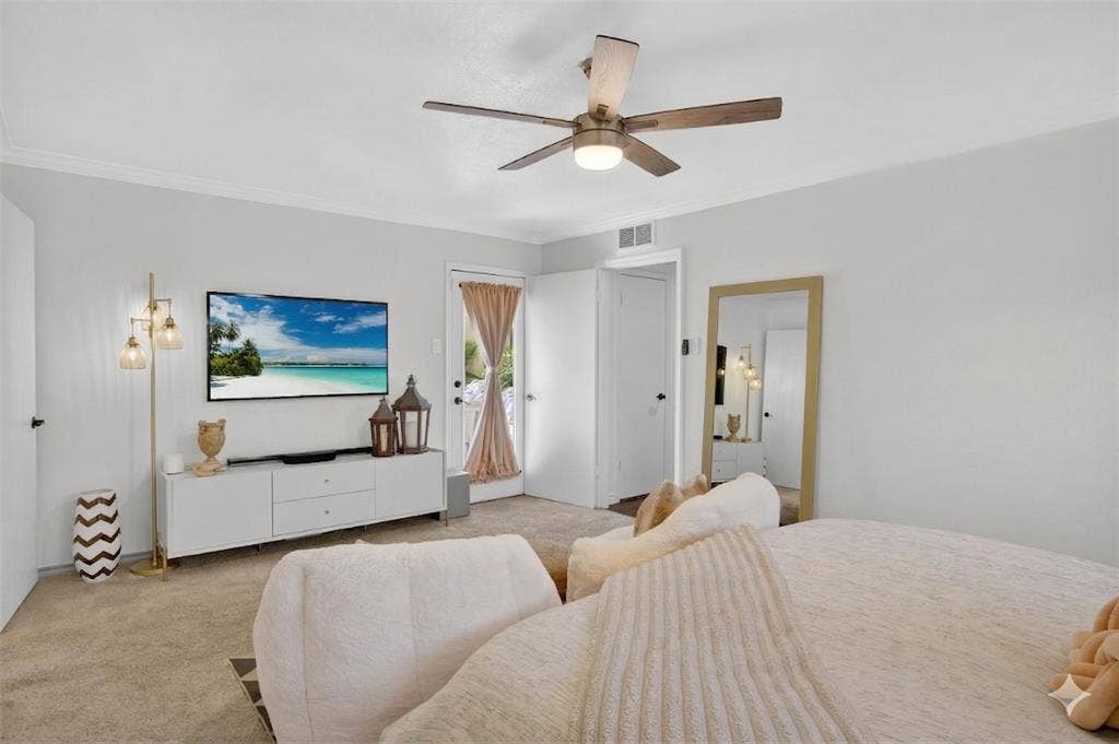 Carpeted bedroom with ceiling fan, access to outside, and ornamental molding