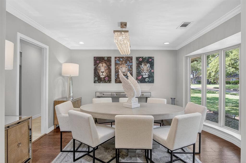 Dining space with suspended lighting, dark wood-style flooring, and crown molding