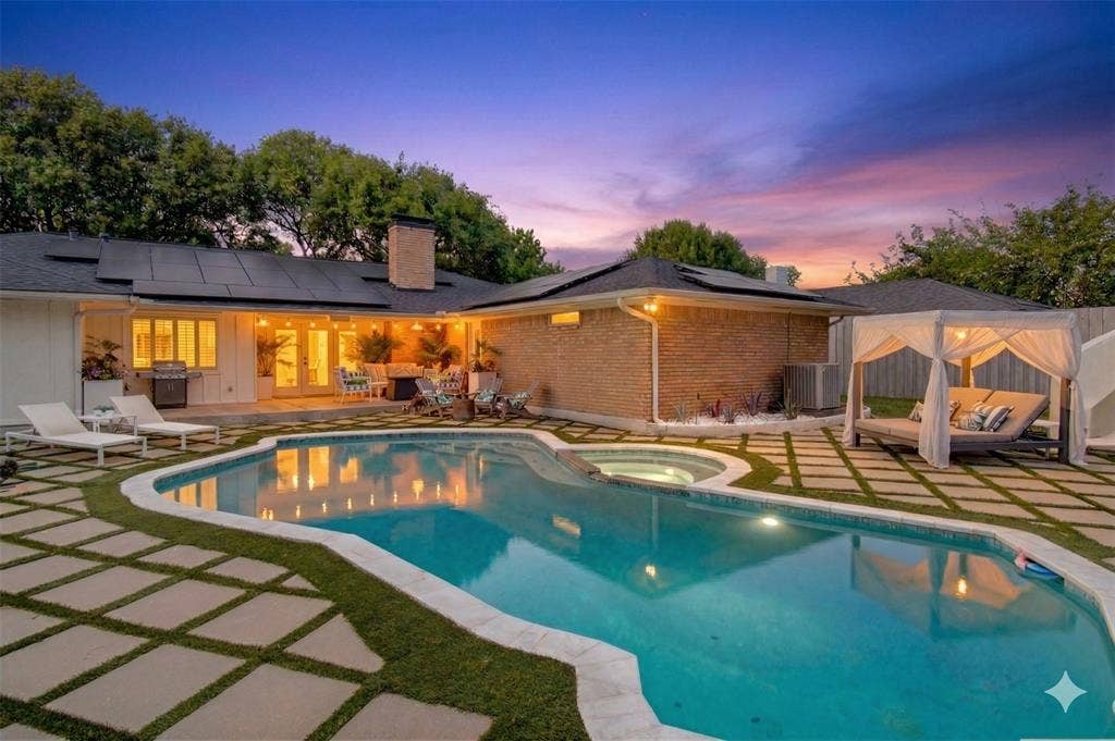 Pool at dusk with a patio, a pool with connected hot tub, a grill, and a fenced backyard