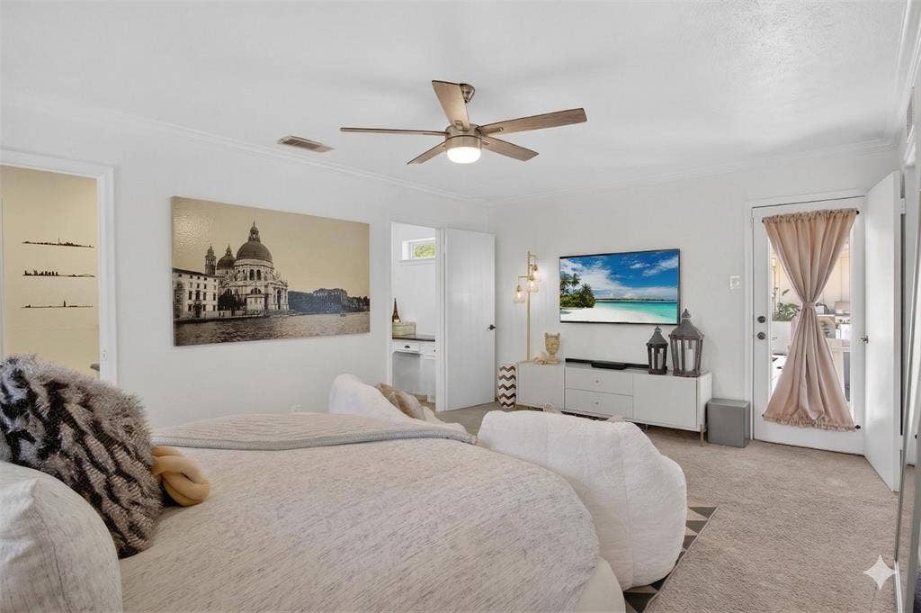 Bedroom with carpet flooring, multiple windows, crown molding, and ceiling fan